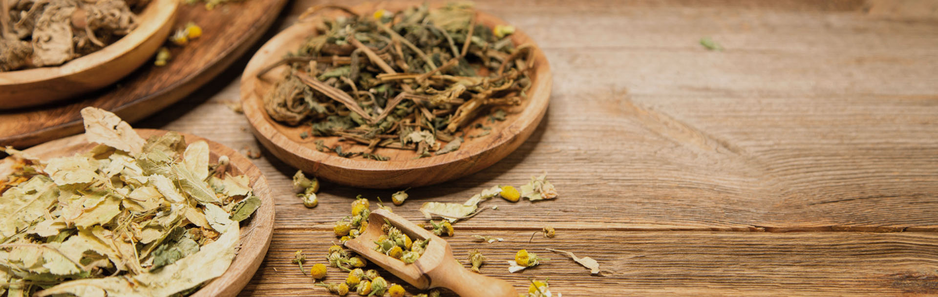 dried leaves, herbs, plants and chamomile lie on a wooden table